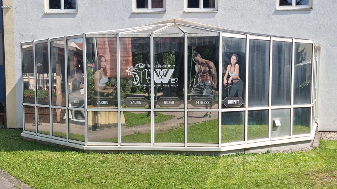 Glasbeschriftung am Wintergarten des Fitness-Studios Löwe mit Personenmotiven und Logo